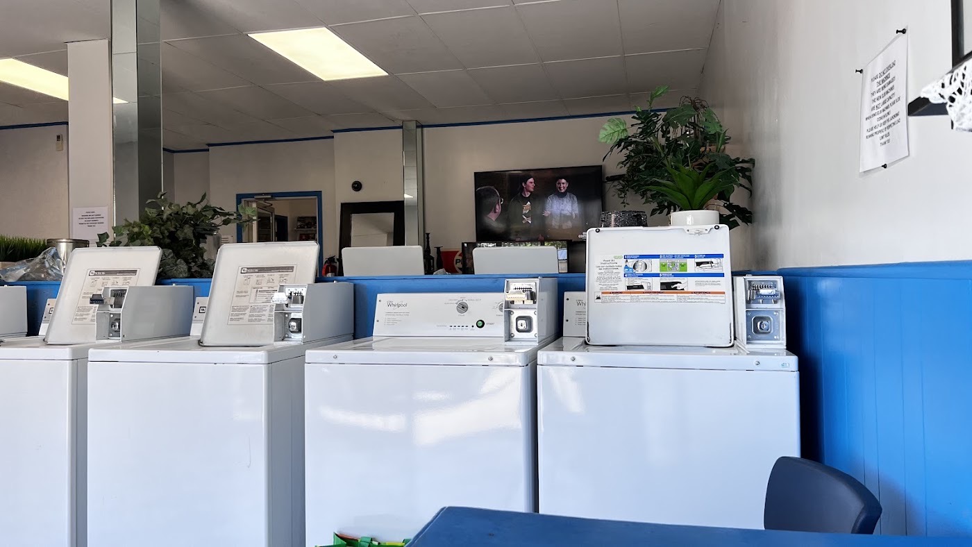 A row of coin-operated top-load washers in the laundromat